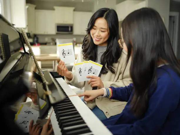piano teacher and student sitting
     at a piano